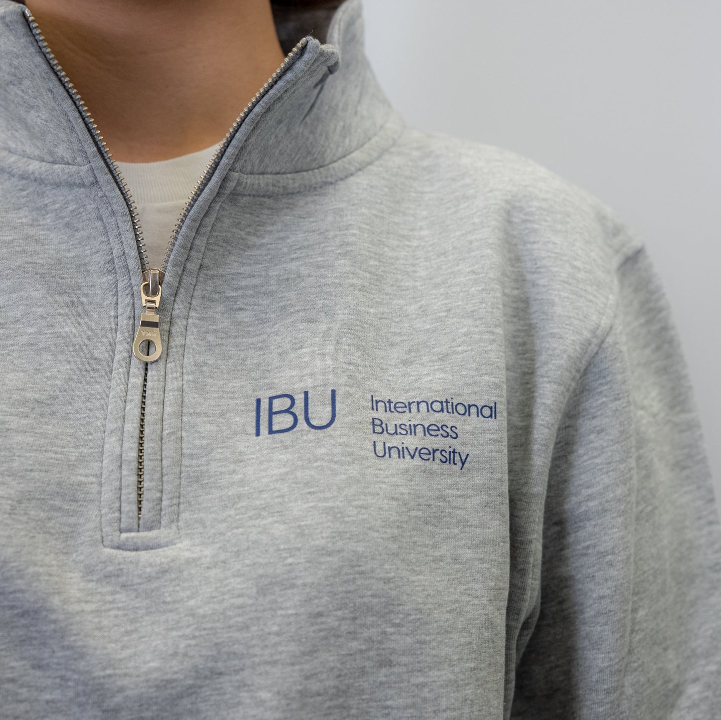 Front view of a woman wearing a grey University Quarter Zip, showing the IBU logo.