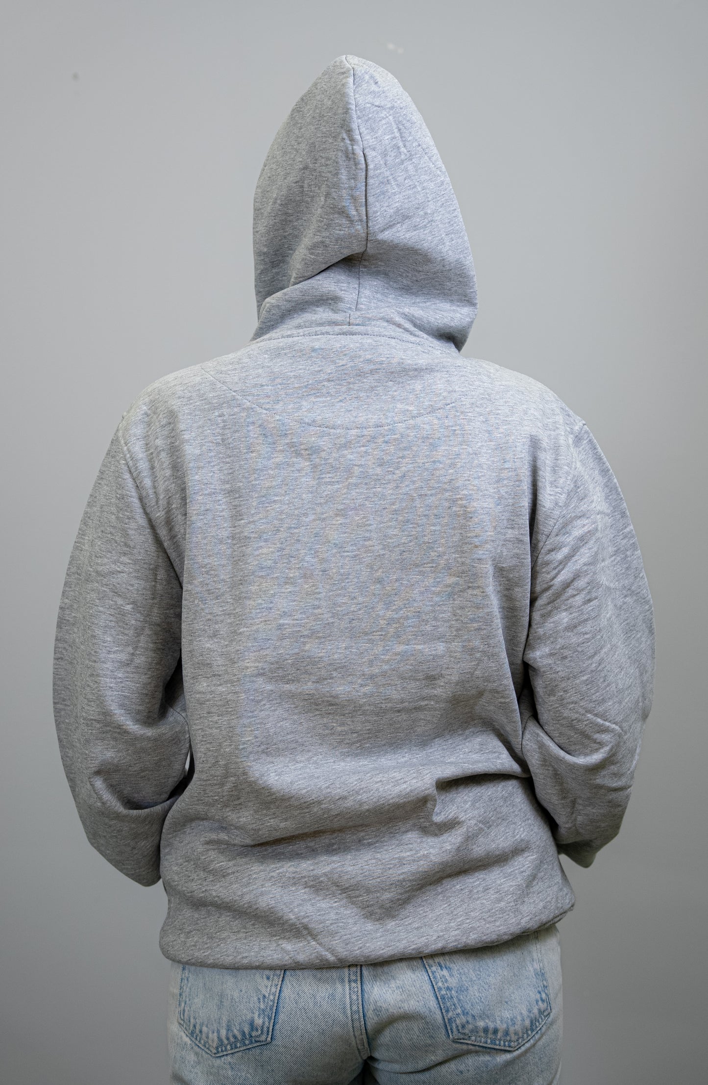 Back view of a grey IBU university hoodie with the hood up, displaying a plain back.