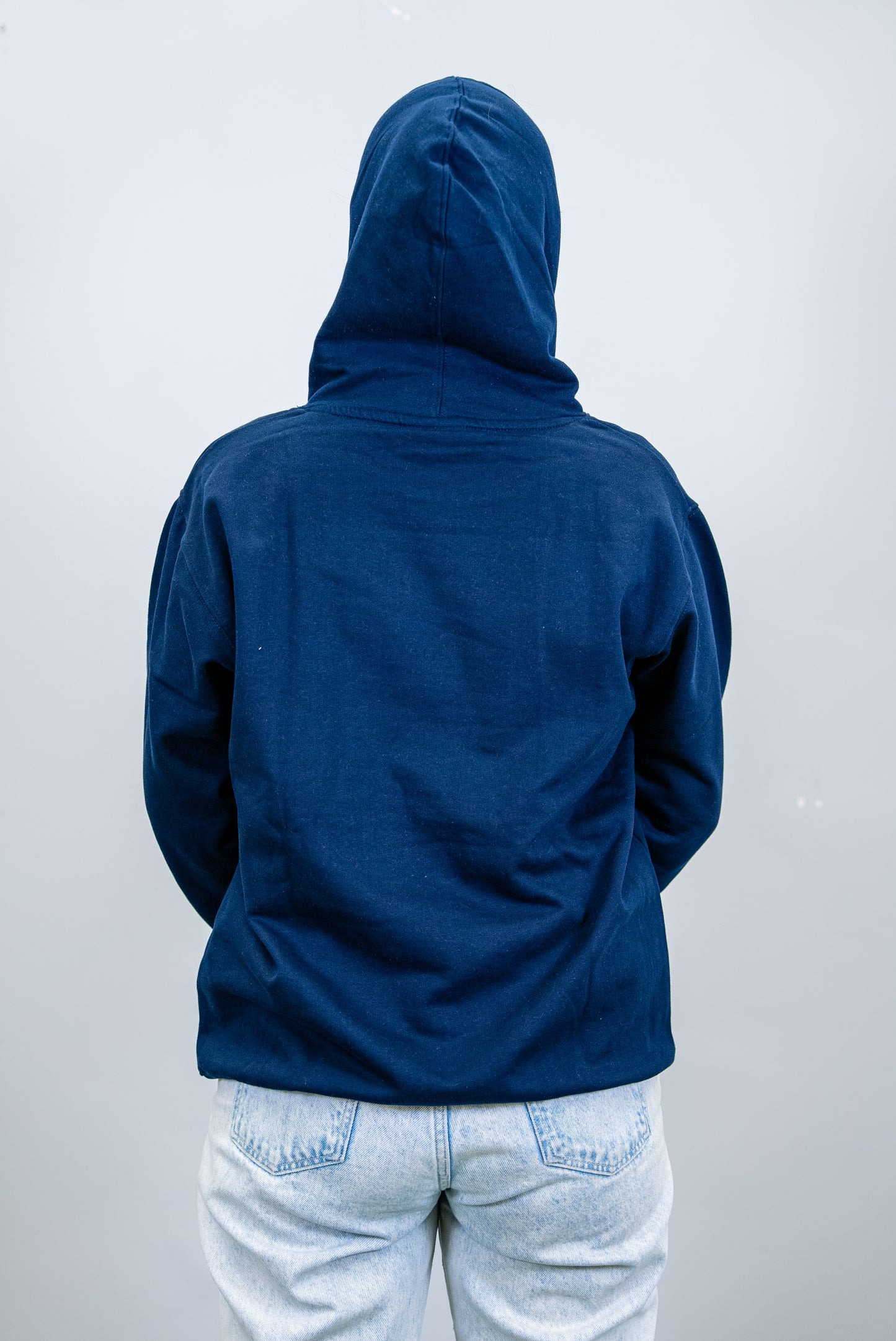 Back view of a navy IBU university hoodie with the hood up, showing a solid rear design.